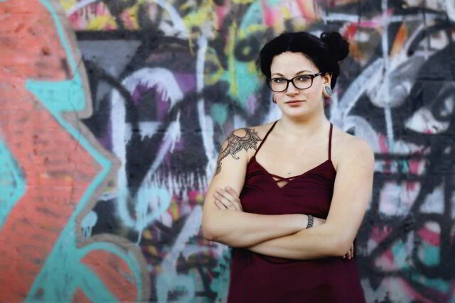 A woman standing in front of a colorful graffiti wall