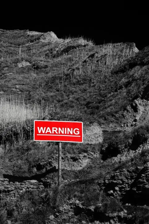 A warning sign beside a mountain path